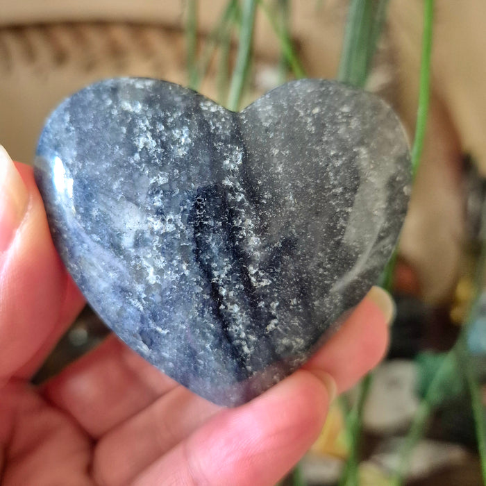 A heart-shaped blue quartz stone being held by a person.