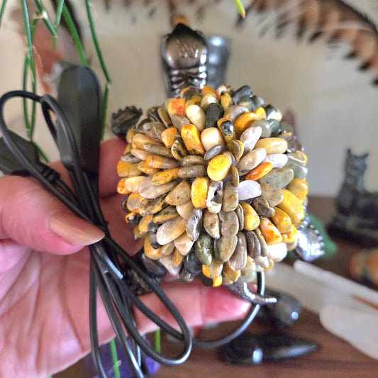 Tortoise-shaped object made of pebbles with a power cord, held by a hand.