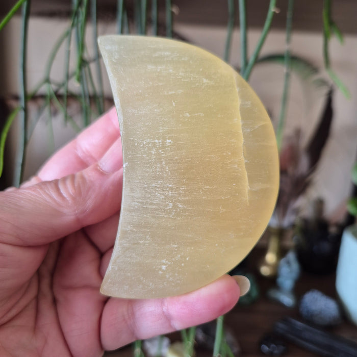 pale lemon colour crescent moon crystal held in a hand
