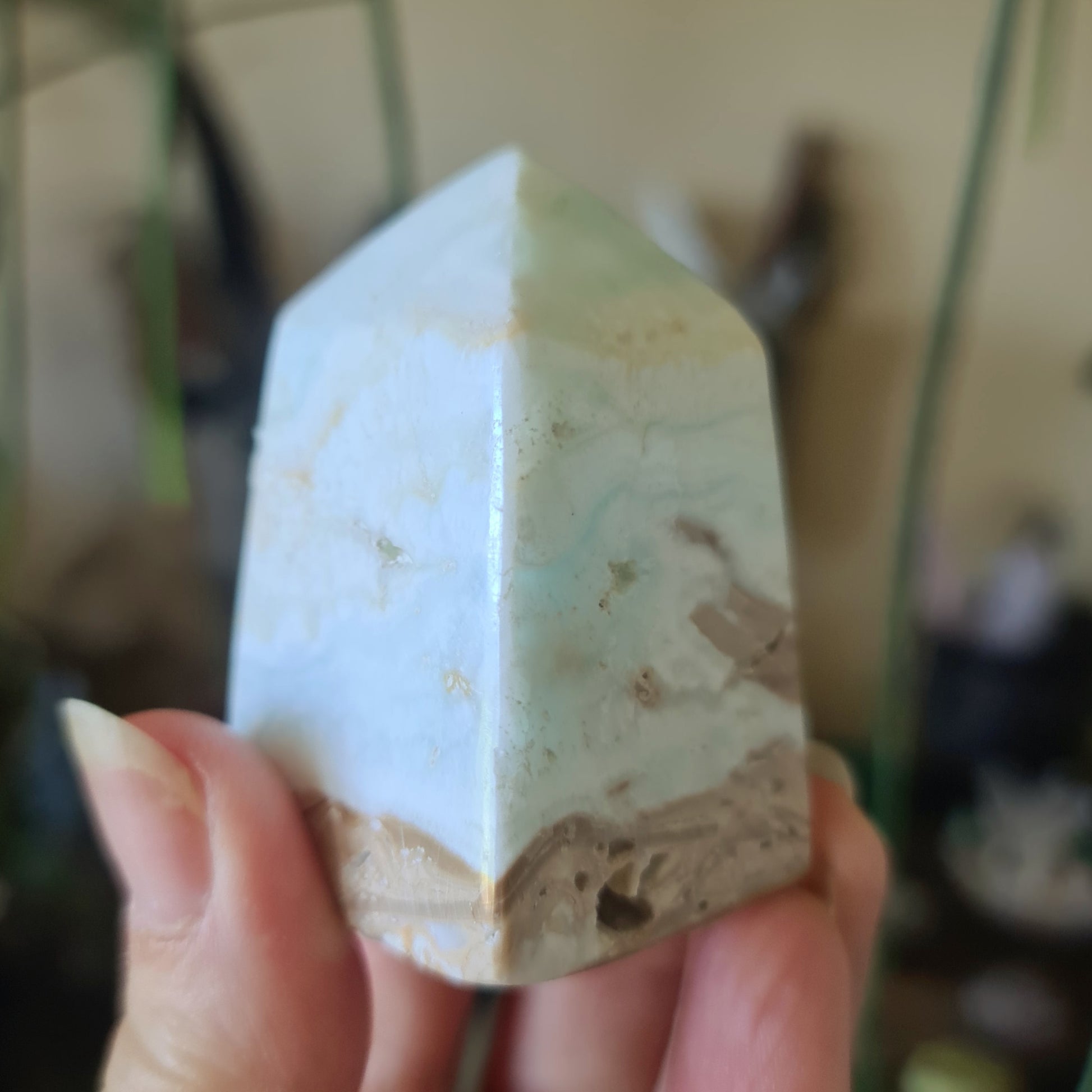 A Caribbean Calcite crystal with a hexagonal base, held in a person's hand.