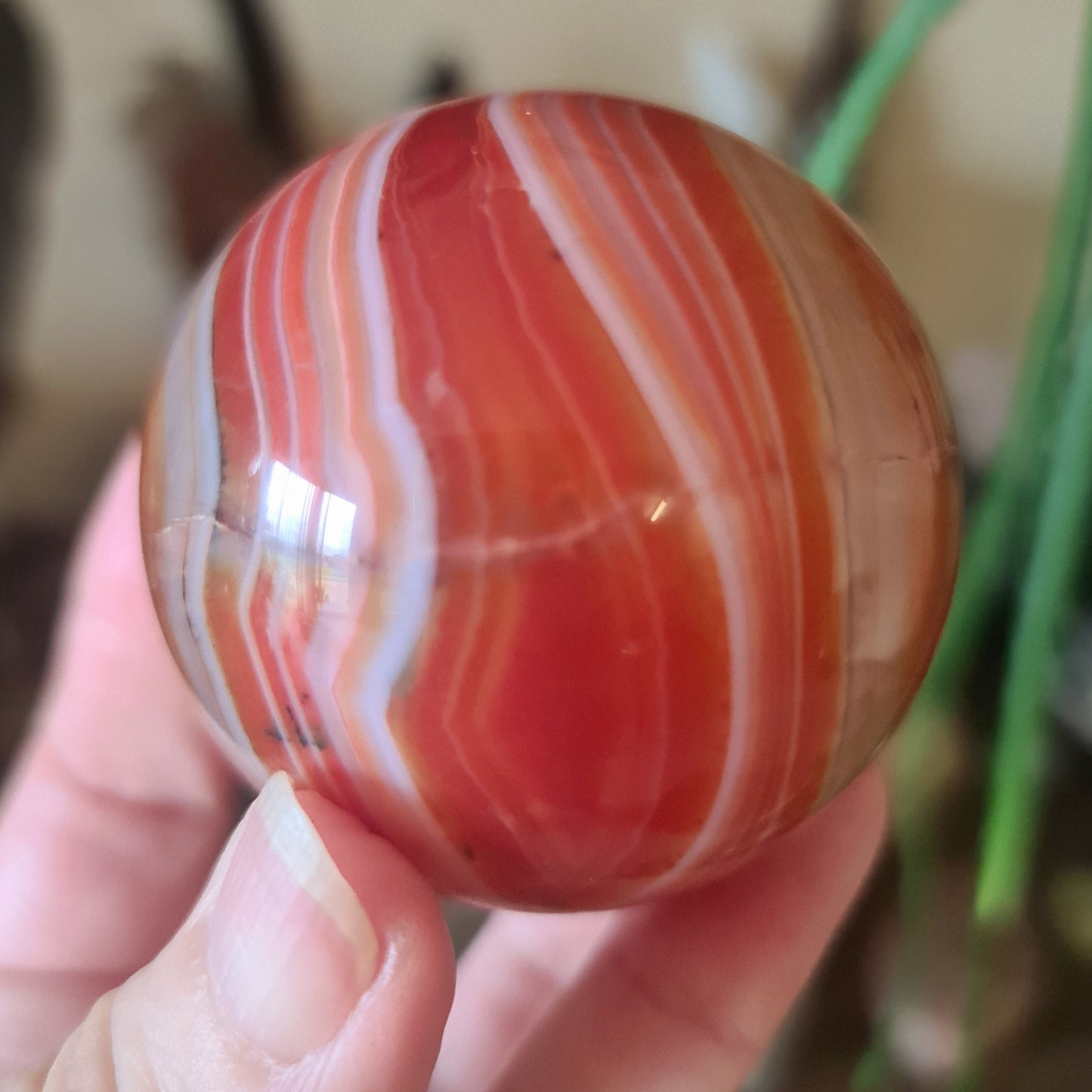 red carnelian crystal sphere held in a hand