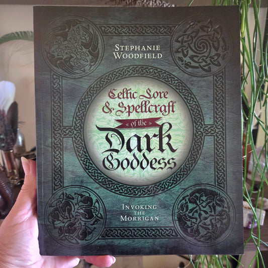 Book titled 'Celtic Lore & Spellcraft of the Dark Goddess' held by a person with decorative background
