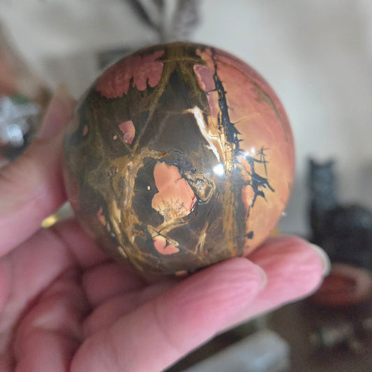 Polished stone with a marbled pattern held in a hand against a blurred background
