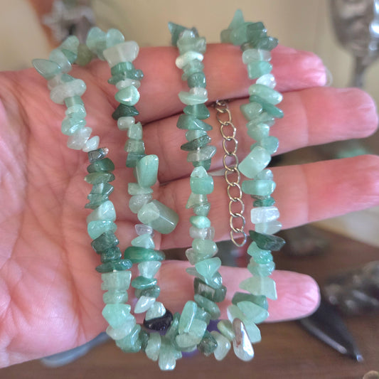 Two green stone necklaces on a hand with a blurred background