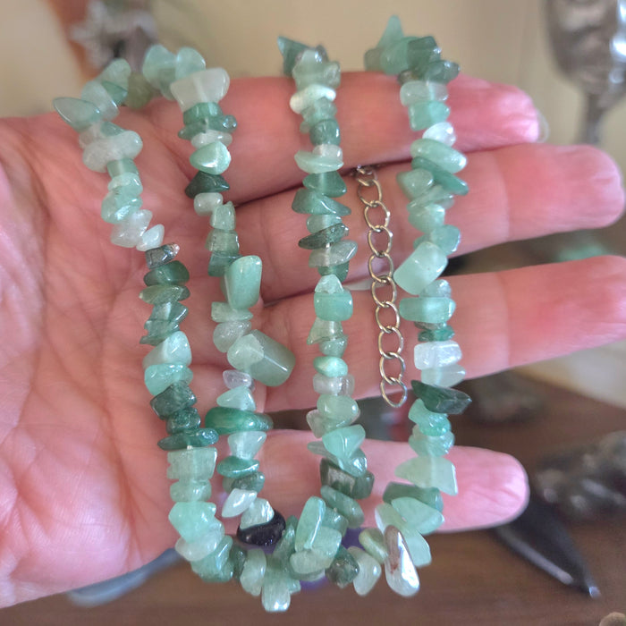 Two green stone necklaces on a hand with a blurred background
