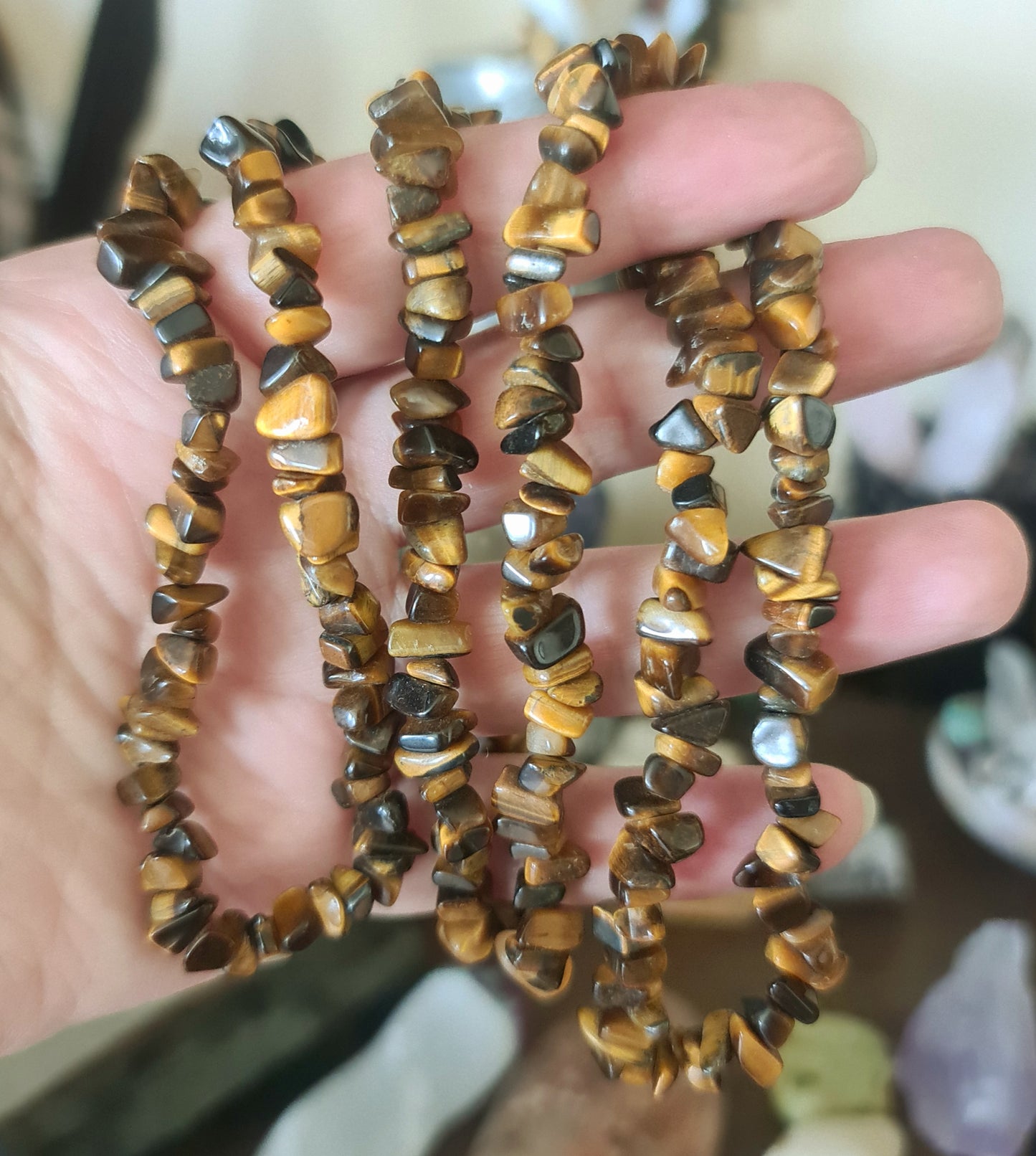 A brown chip necklace with an extended chain, held in a person's hand.