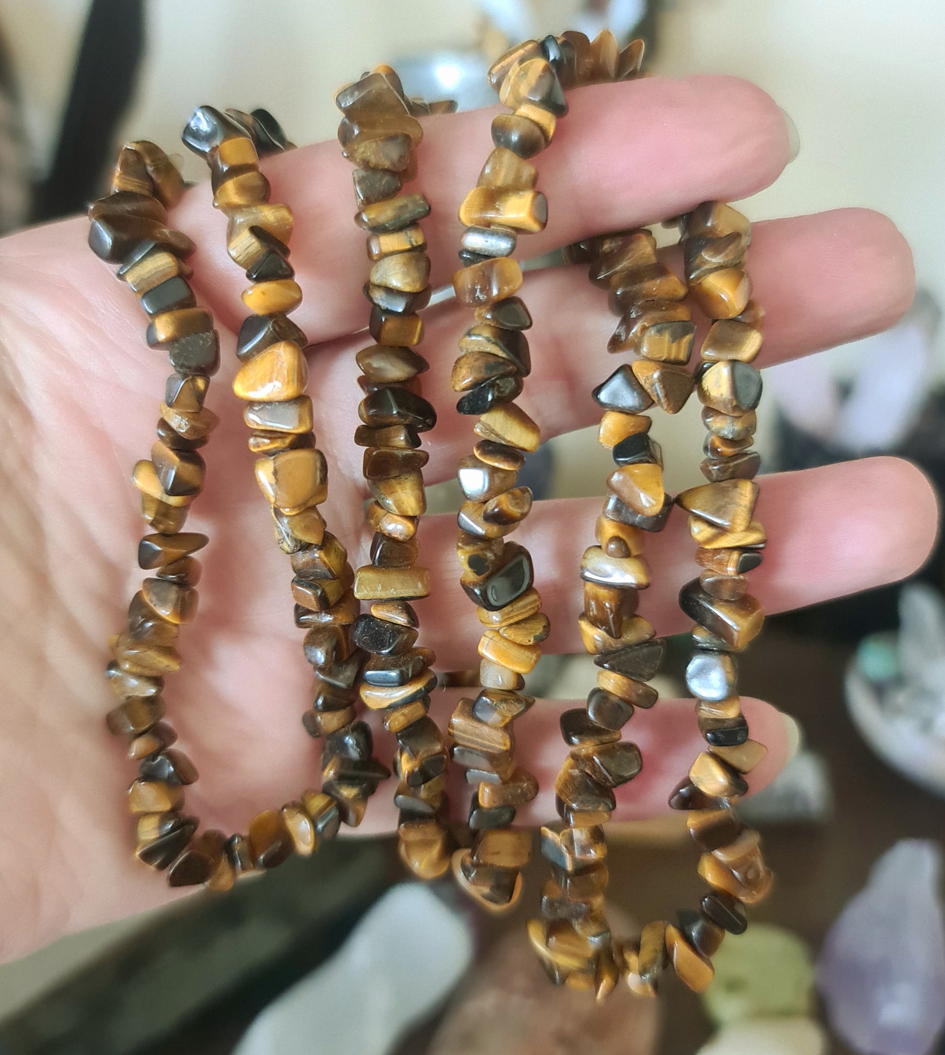 A brown chip necklace with an extended chain, held in a person's hand.