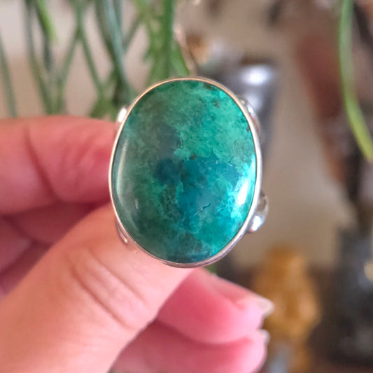 Turquoise stone ring held by a hand with a blurred background