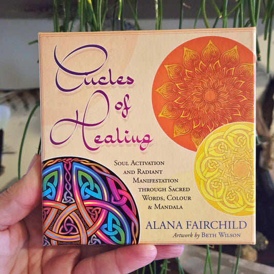 A person holding a pack of 'Circles of Healing' affirmation cards with colorful geometric patterns and mandalas on the cover.