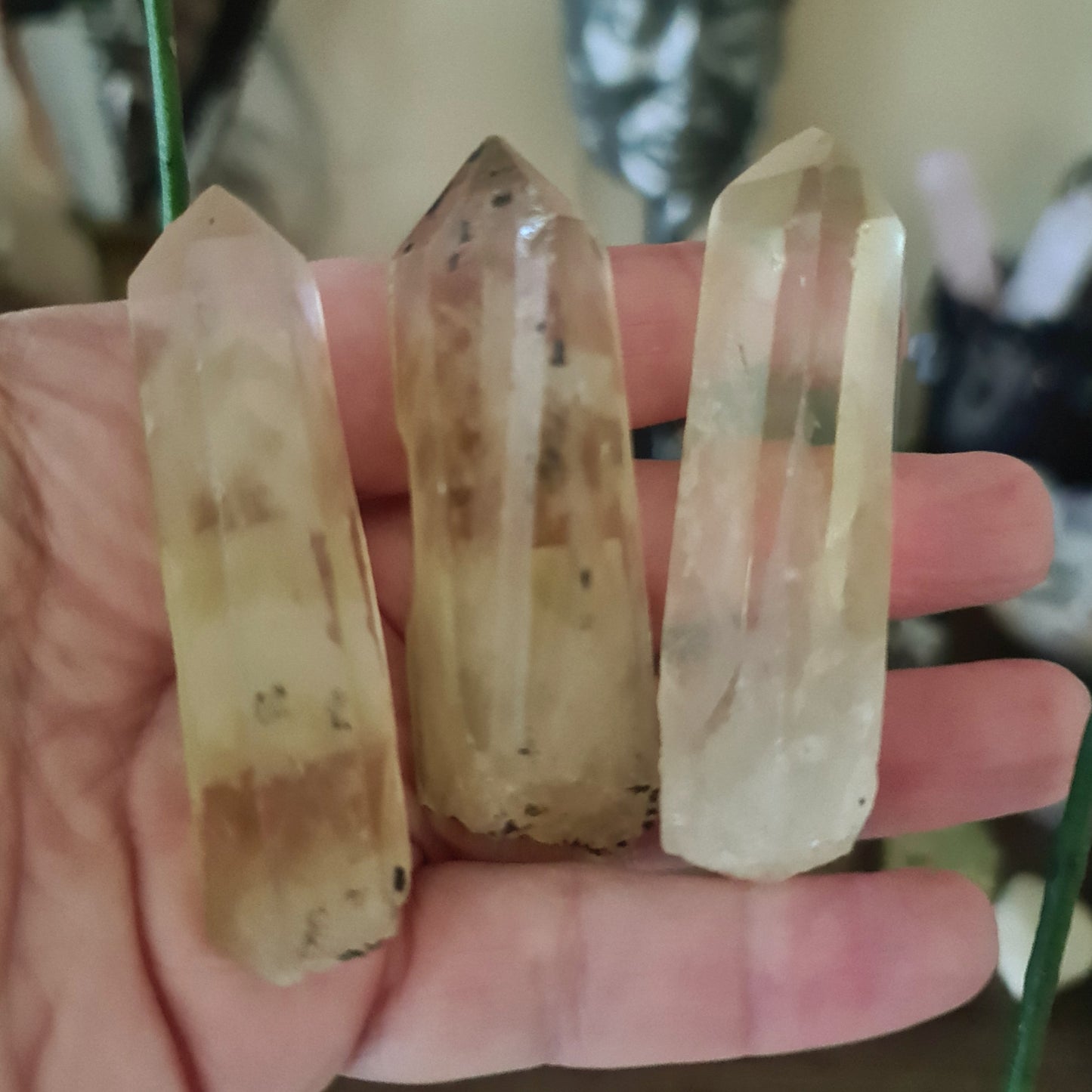 Three polished yellow citrine crystal points, each with a different shape, held in a person's hand.