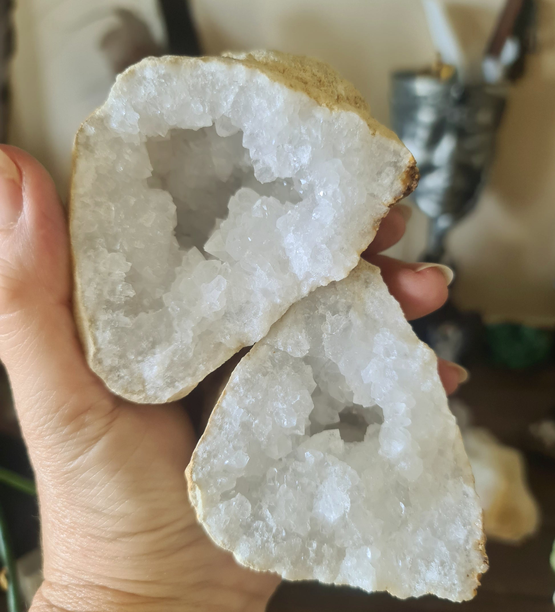 A polished clear quartz crystal geode with a person's hand partially inside, showing the intricate layering of the stone.