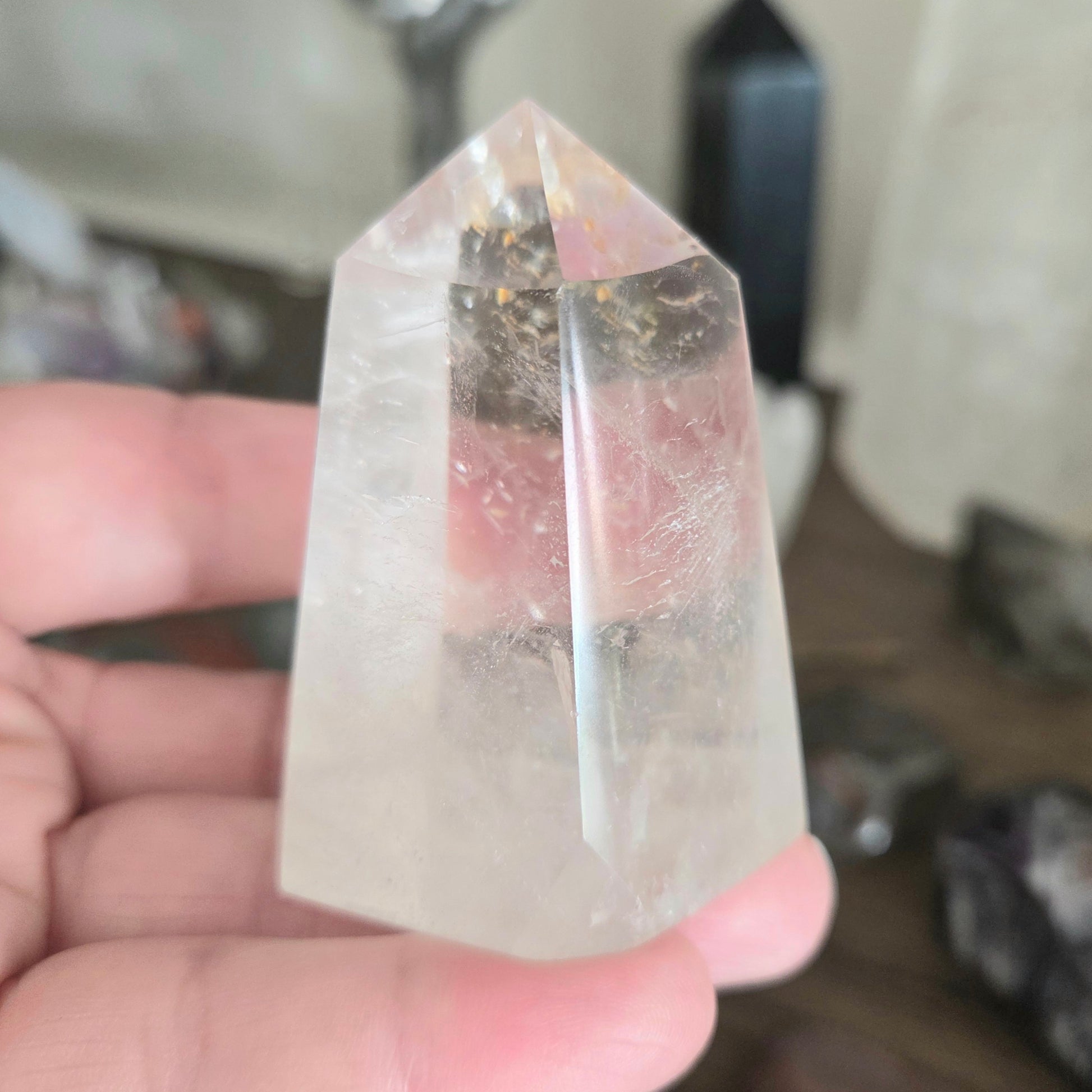 Clear crystal pyramid held in a hand with a blurred background