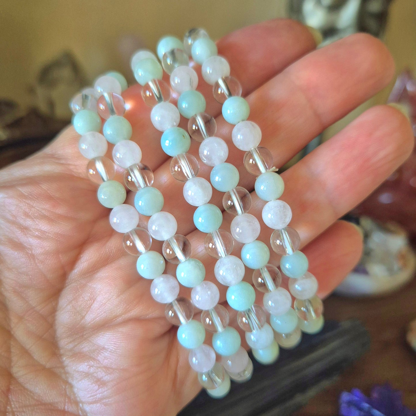 A bracelet with a mix of blue and clear beads held in a hand, featuring a chain-like pattern.