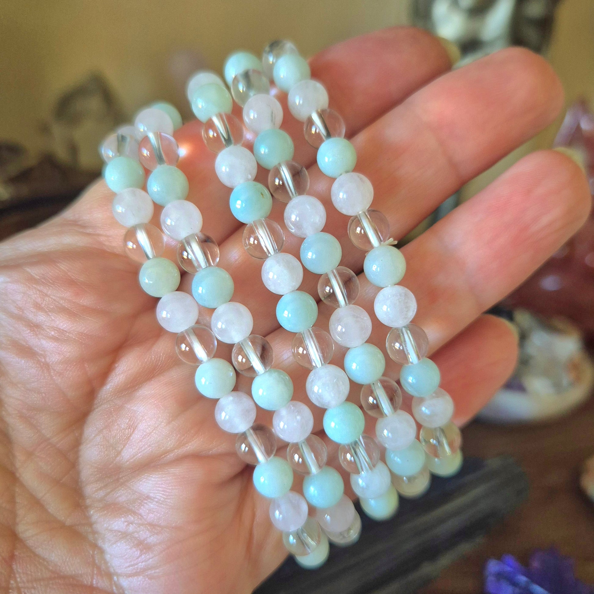 A bracelet with a mix of blue and clear beads held in a hand, featuring a chain-like pattern.