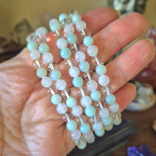 A bracelet with a mix of blue and clear beads held in a hand, featuring a chain-like pattern.