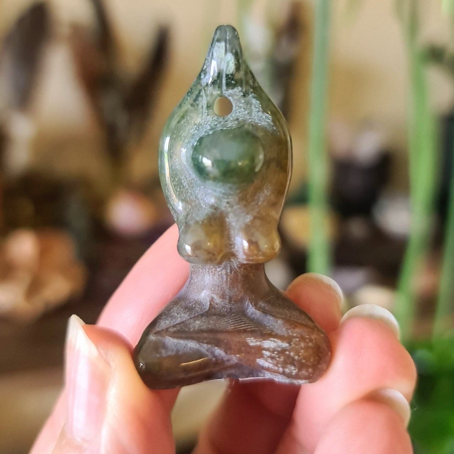 A small brown crystal figurine of a yoga woman figure, held in a person's hand.
