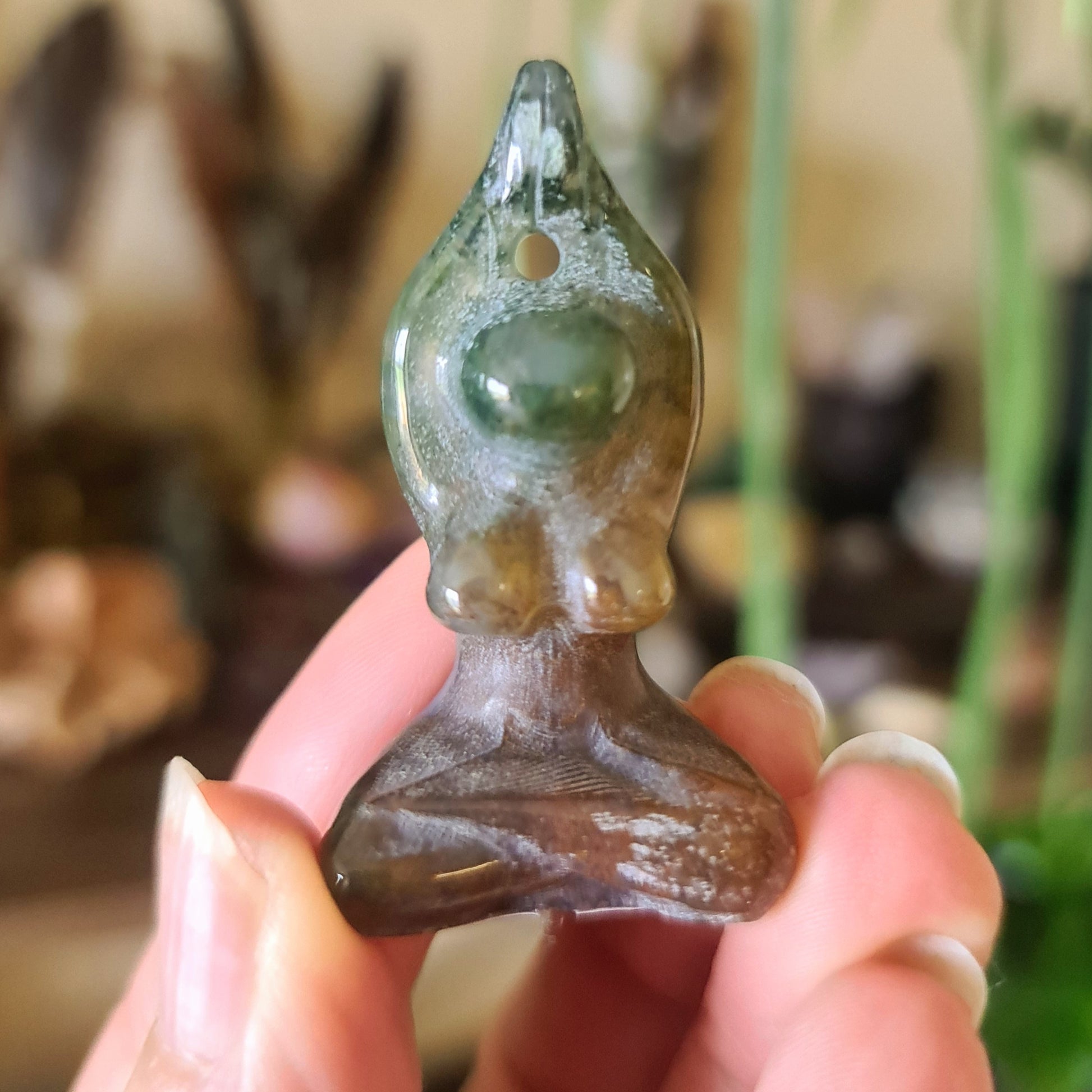 A small brown crystal figurine of a yoga woman figure, held in a person's hand.