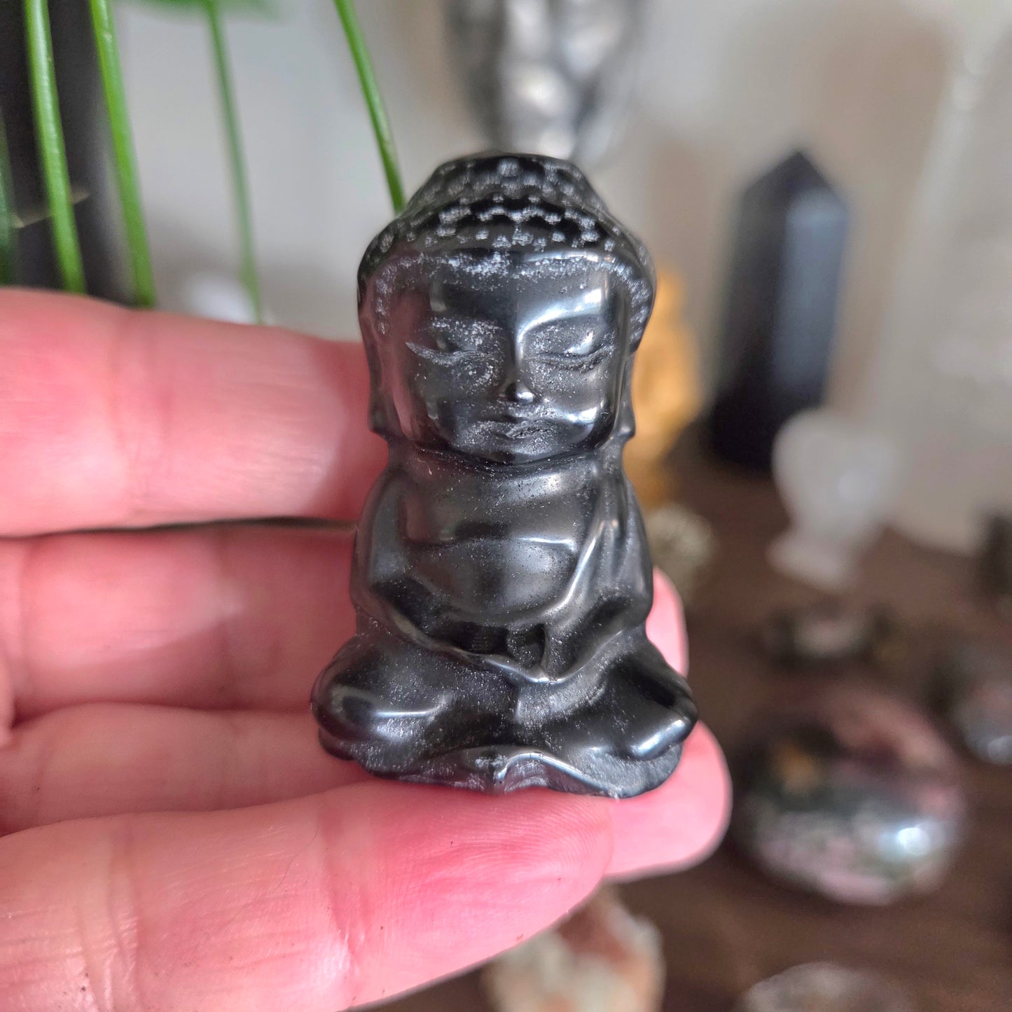 Small black Buddha figurine held in a hand with a blurred background