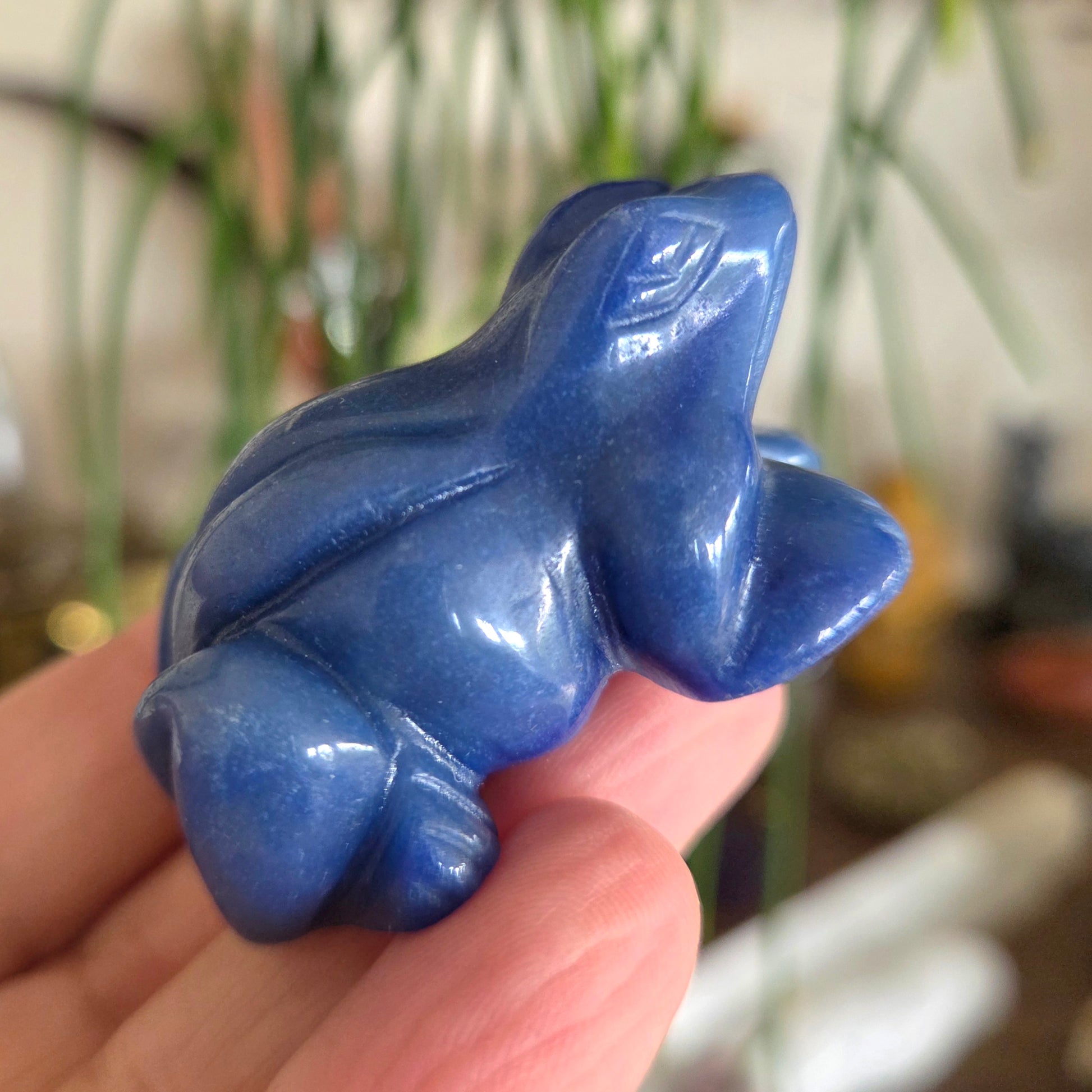 Blue stone sculpture held in a hand with a blurred background