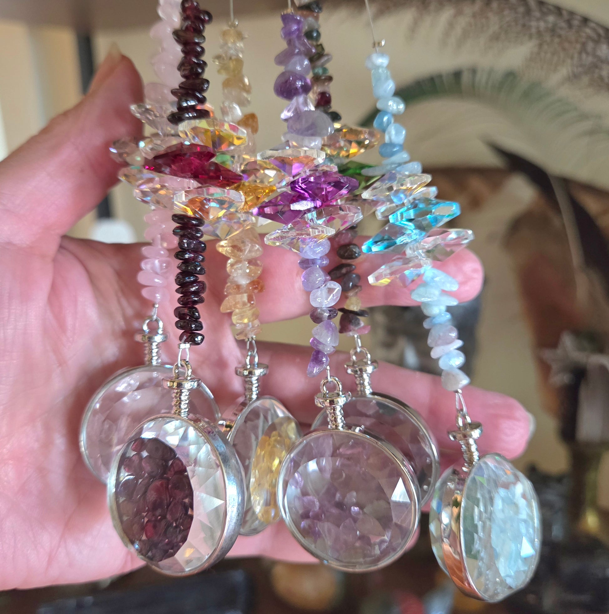 Hand holding a collection of colorful crystal necklaces with various gemstones.
