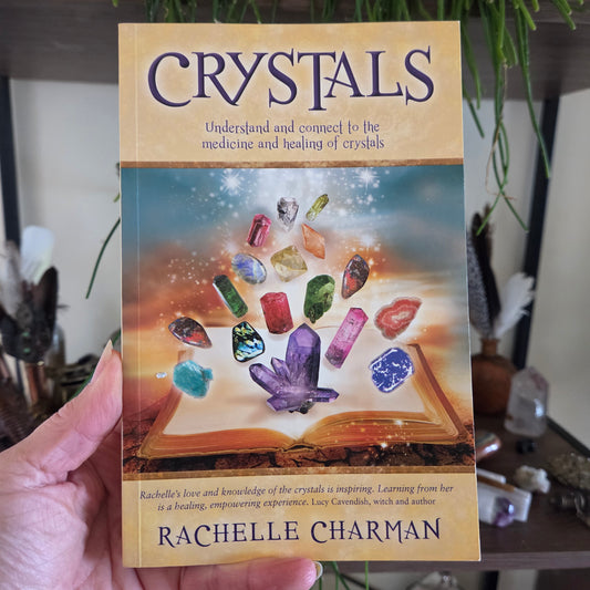 Book titled 'Crystals' by Rachelle Charman held in a hand with a blurred background