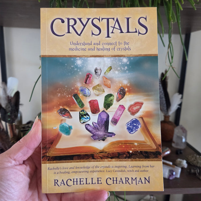 Book titled 'Crystals' by Rachelle Charman held in a hand with a blurred background