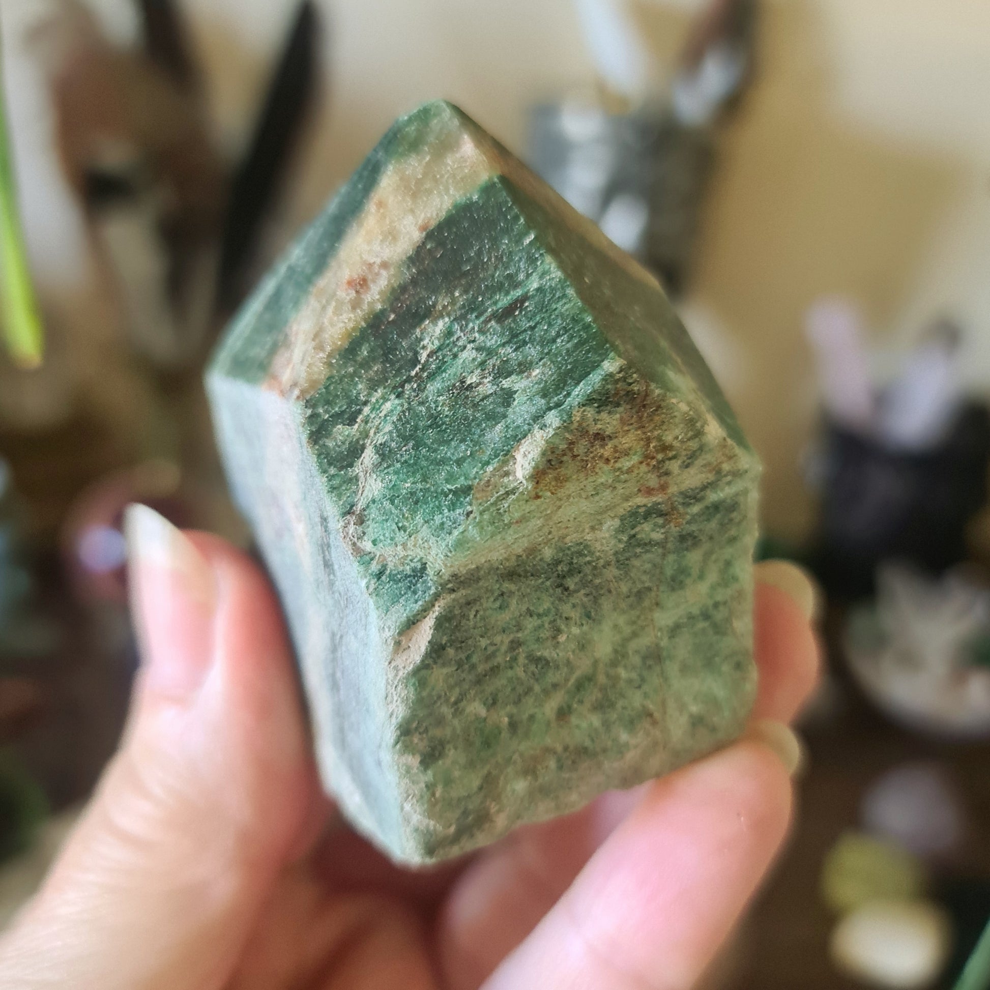 A hand holding a green emerald cut base point.