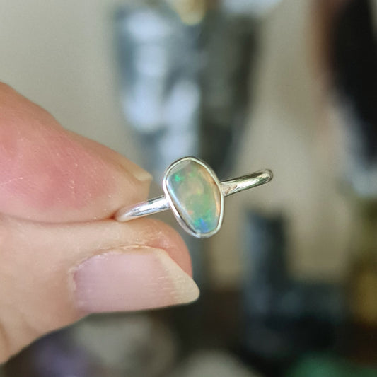 An Ethiopian Opal ring set in a band of 925 Sterling Silver, held between fingers.