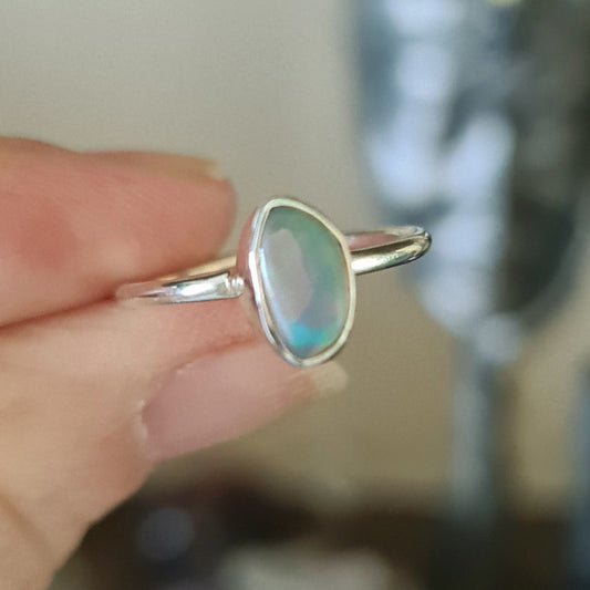 A person holding a size 7 Ethiopian Opal ring with a metallic band.