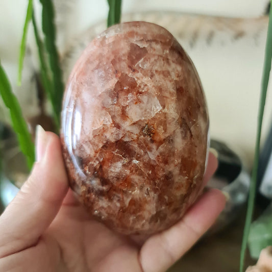 An irregularly shaped polished red Fire Quartz crystal with natural variations in color and texture.