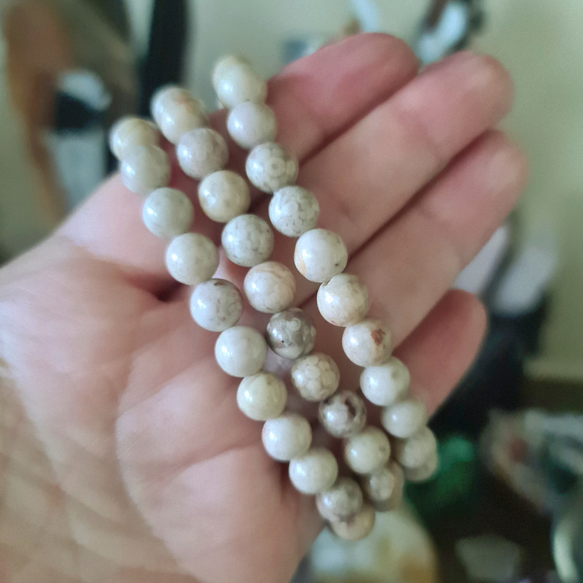 beige beaded bracelet held in a hand