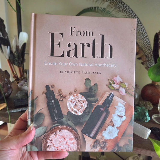 Book titled 'From Earth' by Charlotte Rasmussen held in a hand with a blurred background