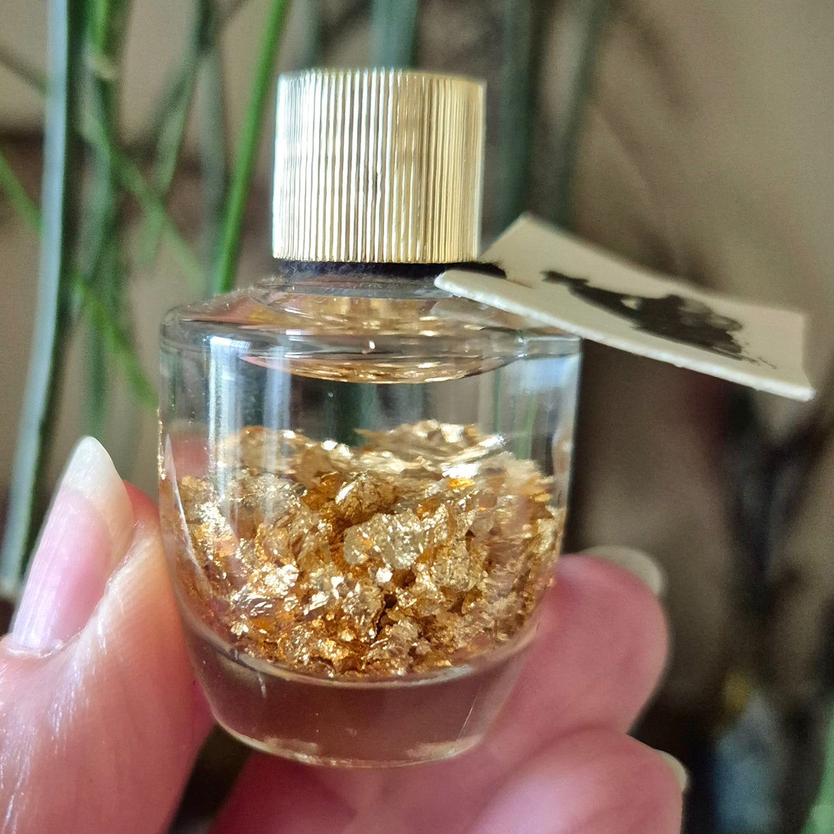 This image features a luxurious Gold Leaf Bottle, elegantly designed with a textured gold leaf surface. The bottle contains a clear liquid, which could be presumed to be a precious oil or cream based on the opulent golden hue of the leaf.