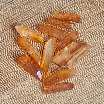 A collection of polished Golden Aura Quartz crystals with a natural golden color on a wooden surface.