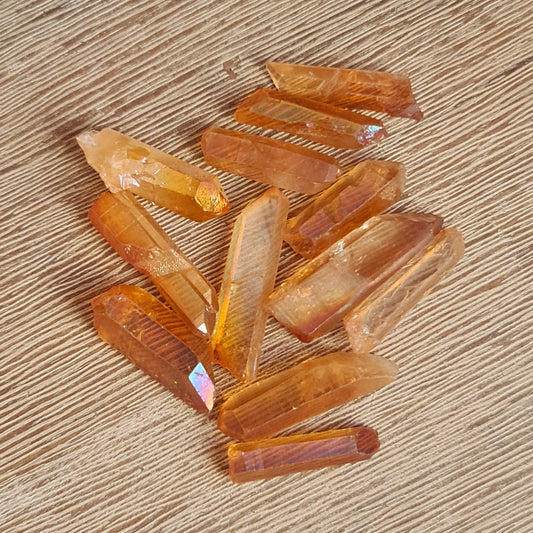 A collection of polished Golden Aura Quartz crystals with a natural golden color on a wooden surface.