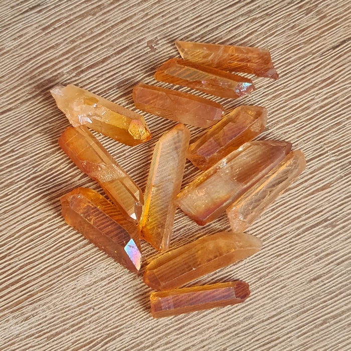 A collection of polished Golden Aura Quartz crystals with a natural golden color on a wooden surface.
