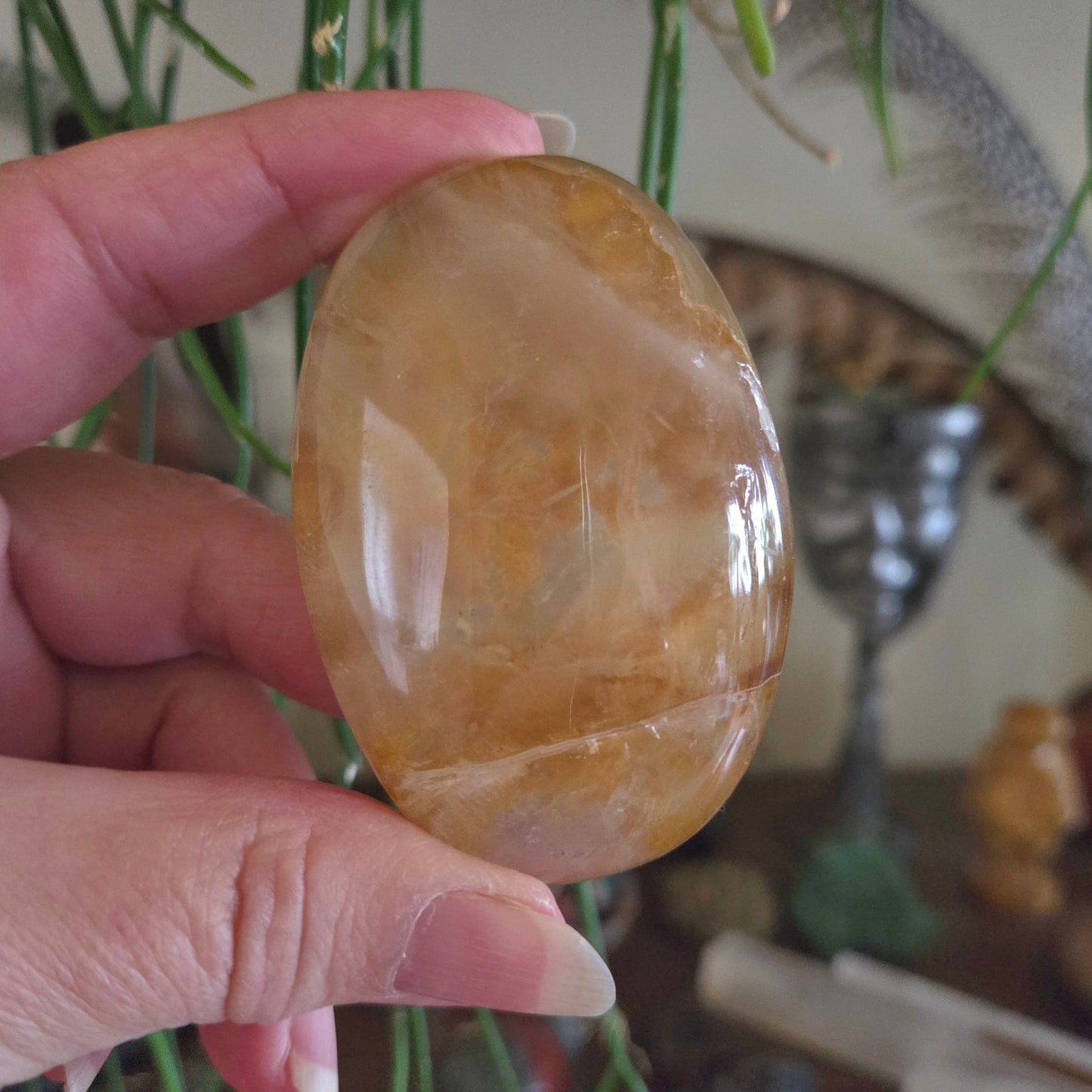 Hand holding a polished stone with a blurred indoor background