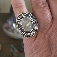 Silver ring with a stone on a person's finger