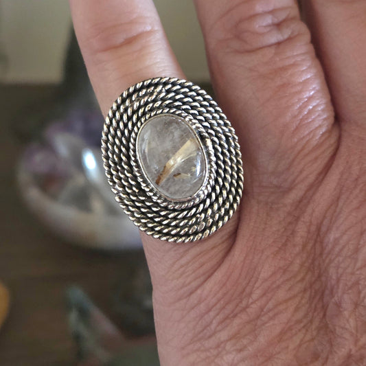Silver ring with a stone on a person's finger