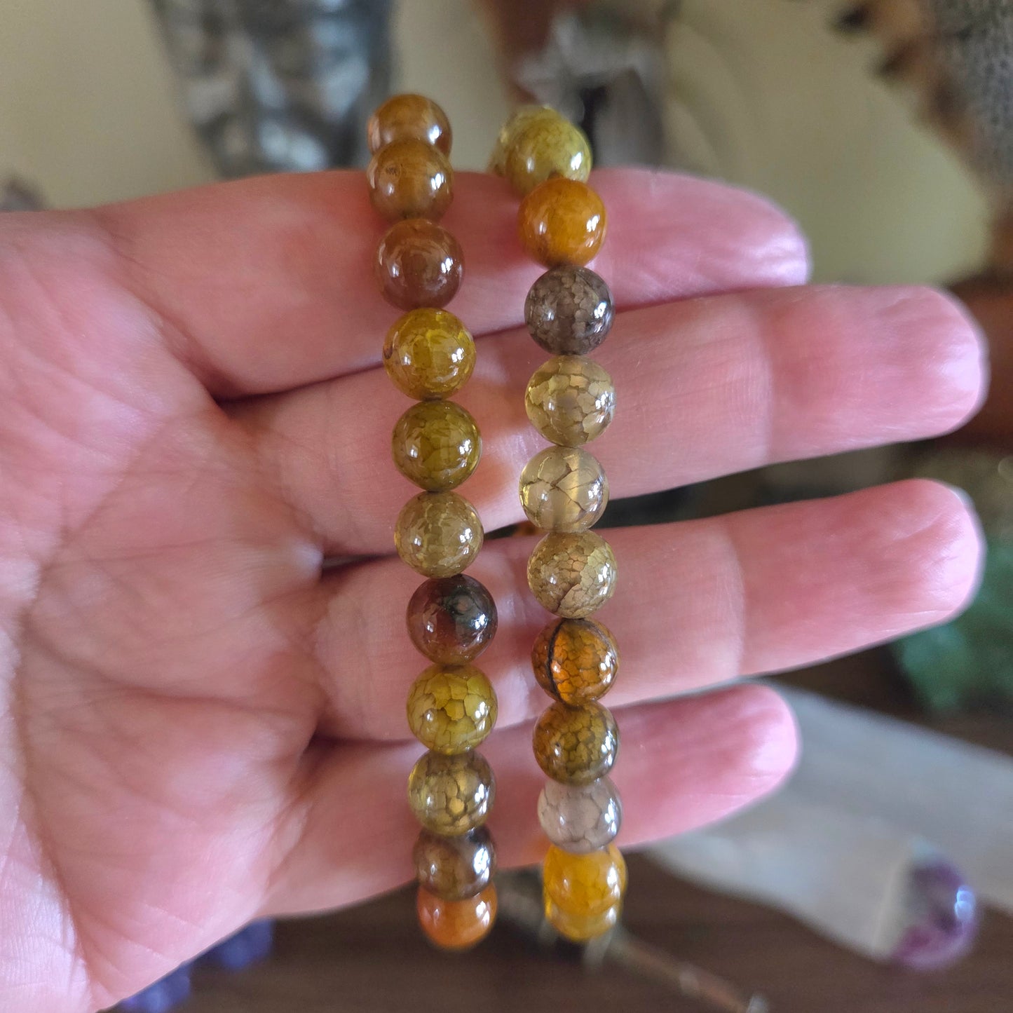 Beaded bracelet with multicolored beads held in a hand against a blurred background