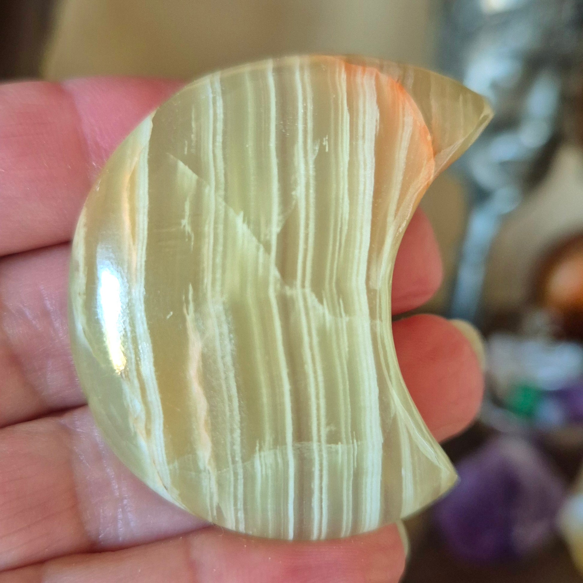 A polished green onyx moonstone held in a person's hand.