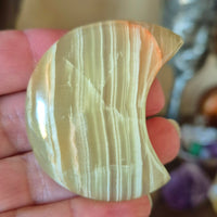 A polished green onyx moonstone held in a person's hand.