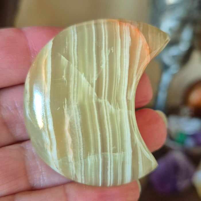 A polished green onyx moonstone held in a person's hand.