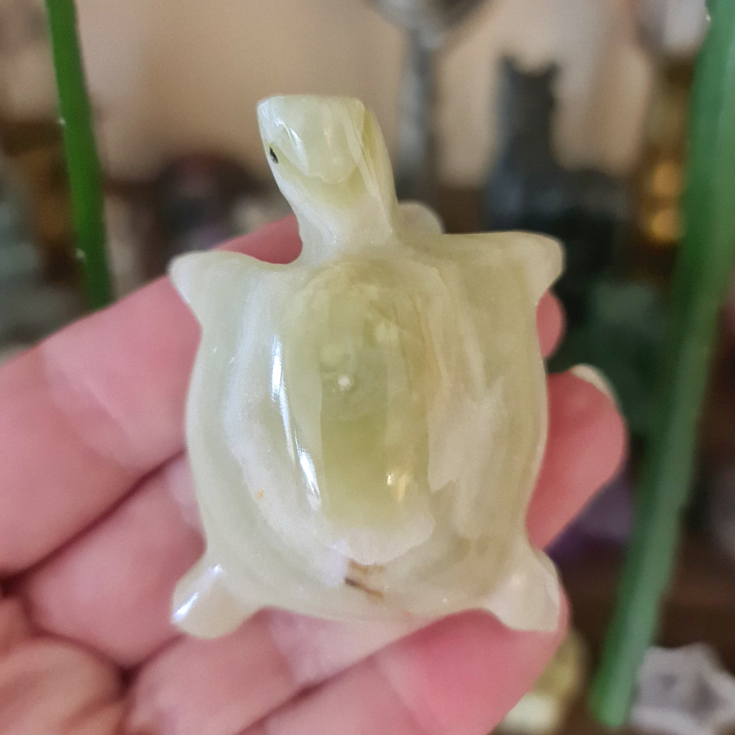 A green onyx turtle figurine held in a person's hand.