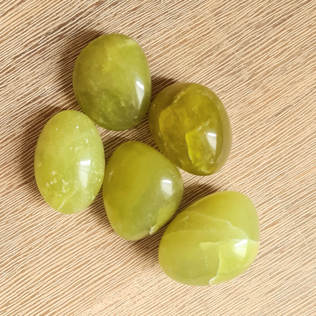 green crystal tumbles on timber background