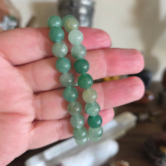 Green beaded bracelet held in a hand with a blurred background