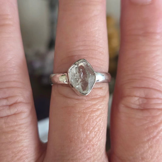 Silver ring with a rough-cut gemstone on a finger