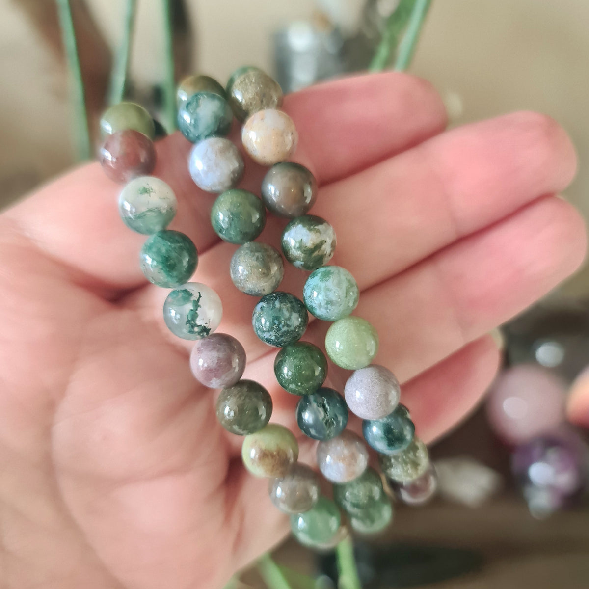 green beaded bracelet held in a hand