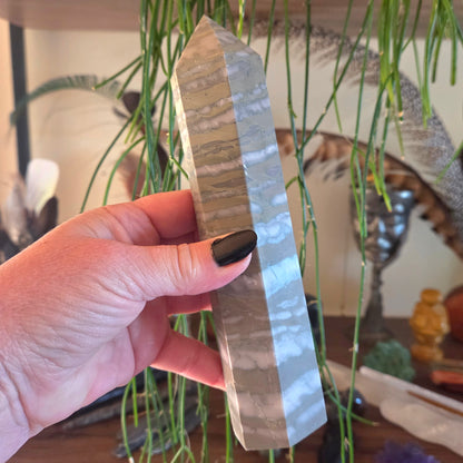 Hand holding a crystal pyramid with a blurred indoor setting