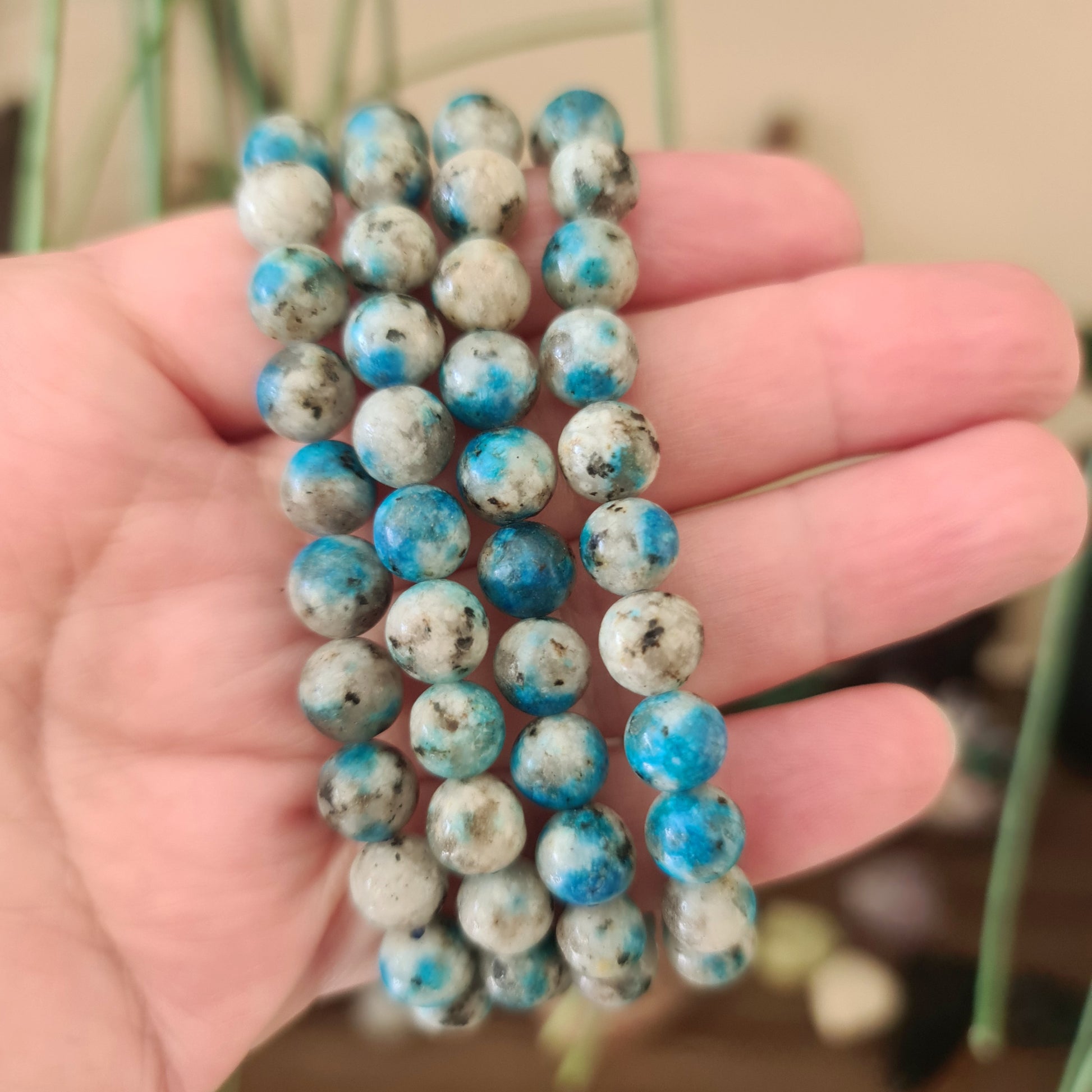 A hand holding a beaded bracelet with blue and white round beads.